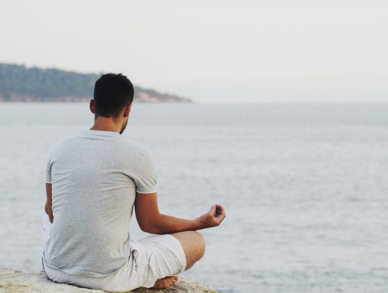 Young man sitting on the coast and meditating